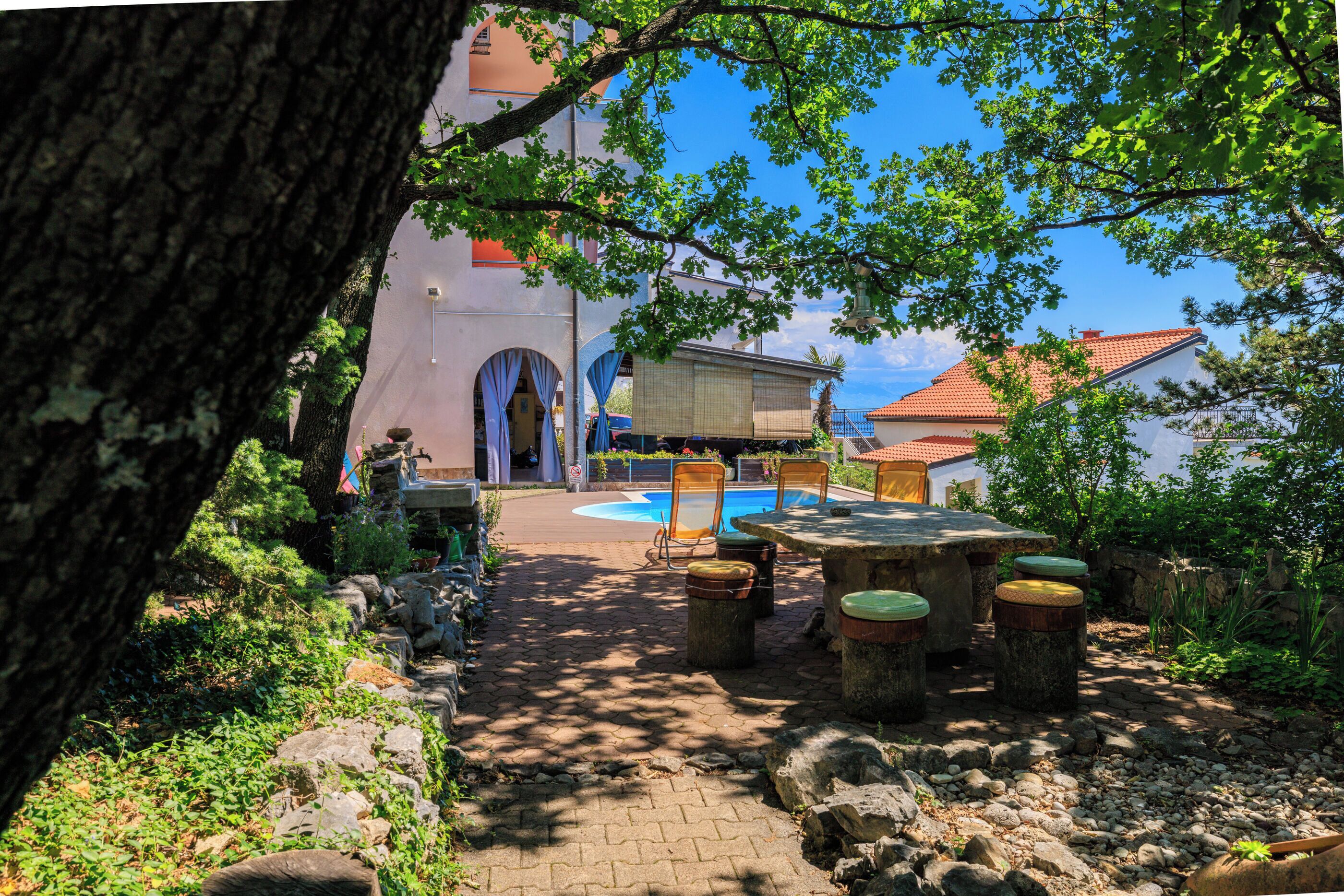 Ein Innenhof mit Pool, Sitzgelegenheiten im Freien und einem Gebäude mit rotem Ziegeldach.