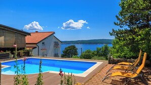 A swimming pool with a view of the sea, a house with a red roof, and a stone wall. - Apartments Djusi (Dramalj)