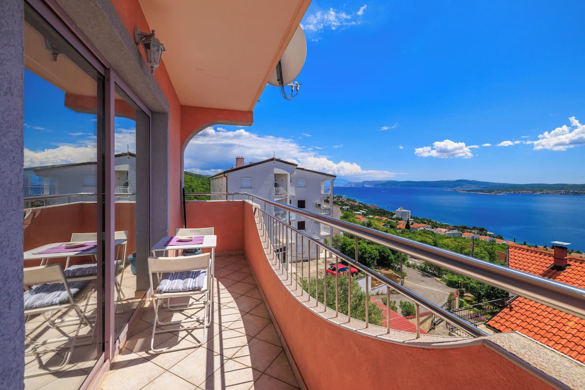 Un balcon avec vue sur la mer, une table avec des chaises et une rambarde.