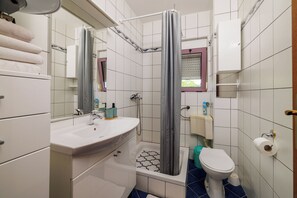 A bathroom with a white sink, a bathtub, a toilet, and a shower curtain. - Apartments Djusi (Dramalj)