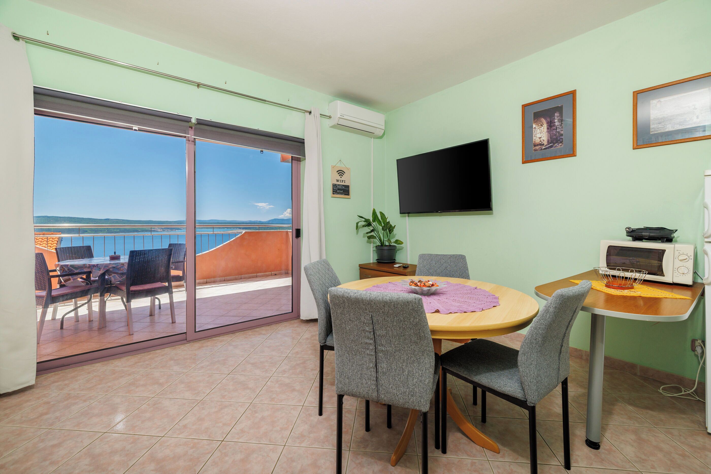 Un espace repas comprenant une table, des chaises, un téléviseur et une vue sur la mer.