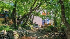 A stone pathway leading to a bench, surrounded by greenery and stone walls. - Apartments Djusi (Dramalj)