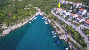Vue aérienne d’une zone côtière avec un port de plaisance, des bateaux et des immeubles résidentiels.