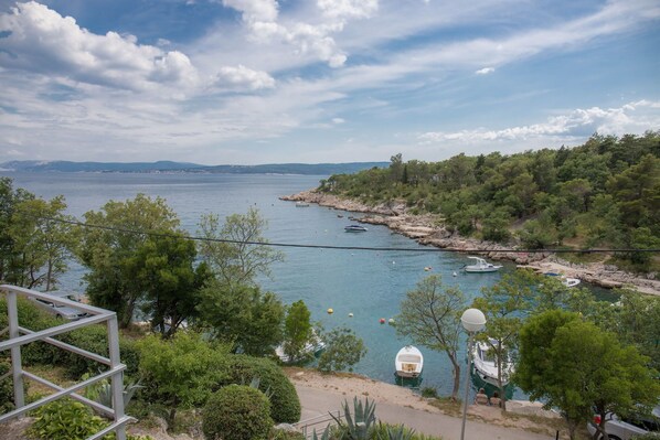 A coastal view with a rocky shoreline, boats, and a clear sky.
