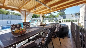 An outdoor patio with a pool, wooden ceiling, and outdoor seating.