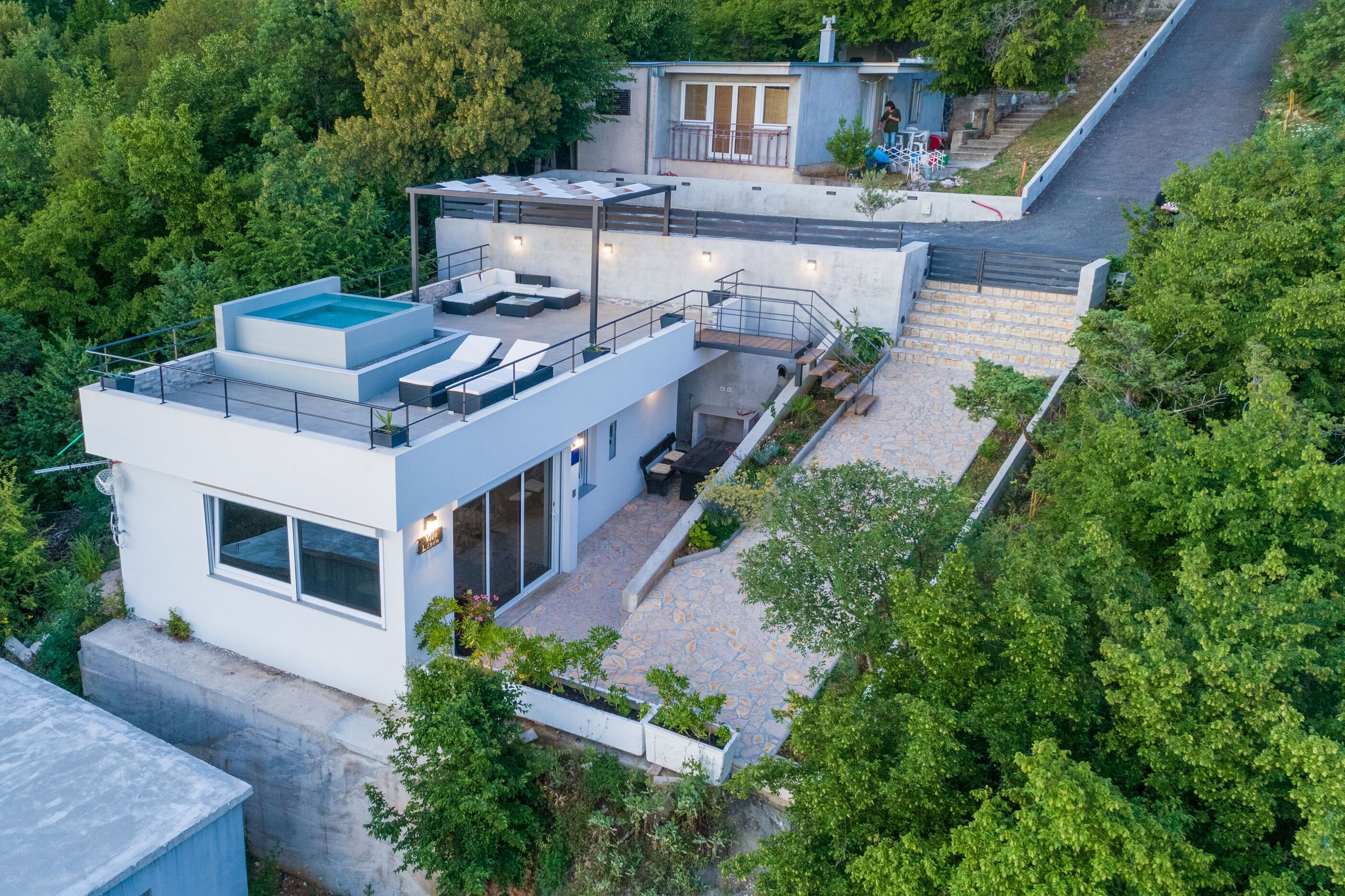 A modern house with a rooftop pool, a covered patio, and a staircase leading to a second level.