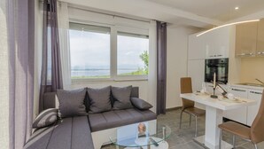 A modern living room with a sofa, a glass coffee table, and a view of the outdoors. - House Linda 2 (Crikvenica)