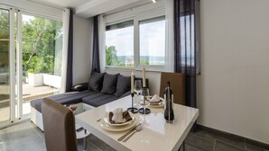 A modern dining area with a table set for two, a sofa, and a view of the outdoors. - House Linda 2 (Crikvenica)