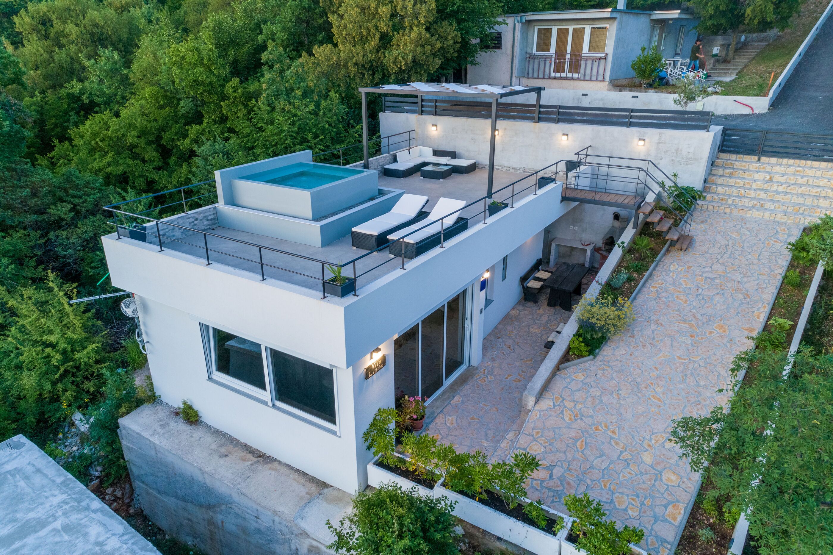 Una casa moderna con piscina en la azotea, mobiliario exterior y un camino de piedra.