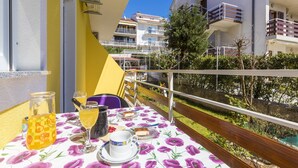 A balcony with a table set for two, featuring a floral tablecloth, a glass of orange juice, a cup, and a small plate of food. - Apartment Lena (Crikvenica)