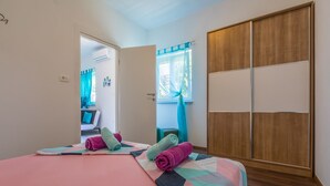 A bedroom with a bed, a wooden wardrobe, and a window with curtains. - Apartment Lena (Crikvenica)