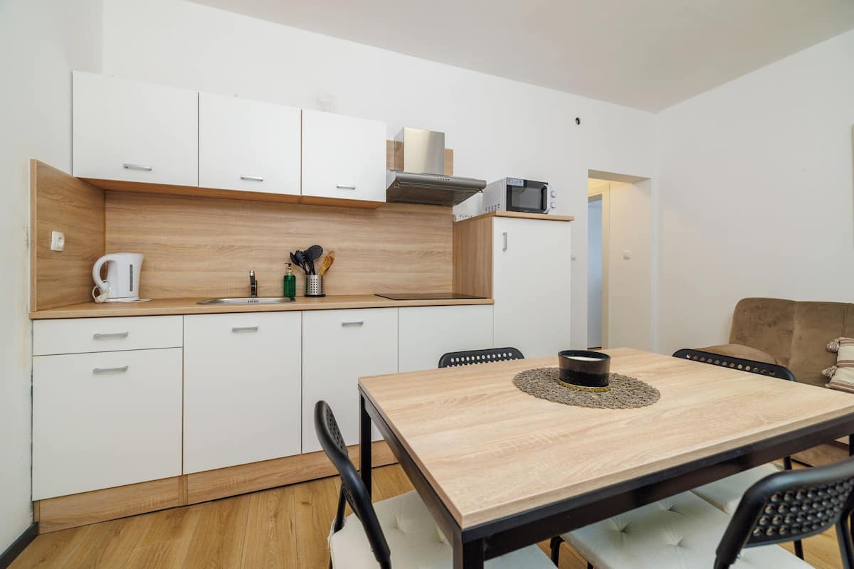 A compact kitchen with white cabinets, a wooden countertop, and a dining area with a table and chairs.