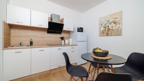 Eine moderne Küche mit weißen Schränken, einer schwarzen Arbeitsplatte und einem Essbereich mit schwarzen Stühlen und einem kleinen Tisch.