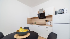 Eine moderne Küche mit weißen Schränken, einer schwarzen Arbeitsplatte und einem weißen Kühlschrank.
