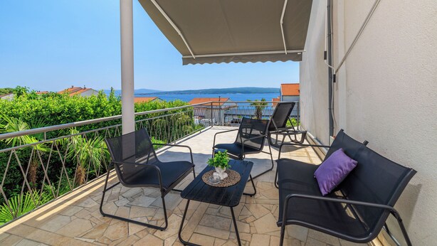 Ein überdachter Sitzbereich mit Blick auf das Meer und die Hügel.