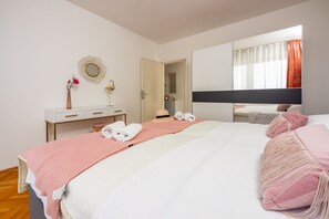 A bedroom with a bed, a dresser, a mirror, and a window with curtains.