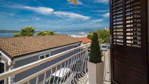 A balcony with a view of the sea, a tiled roof, and a dark wooden door. - Apartments Latino (Crikvenica)