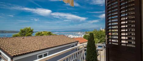 A balcony with a view of the sea, a tiled roof, and a dark wooden door.