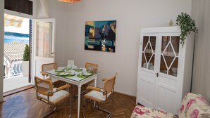A dining area with a glass table, wicker chairs, a white cabinet, and a painting on the wall. - Apartments Latino (Crikvenica)