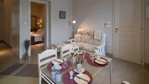 A cozy living room with a sofa, a dining table set for two, and a door leading to another room. - Apartments Latino (Crikvenica)