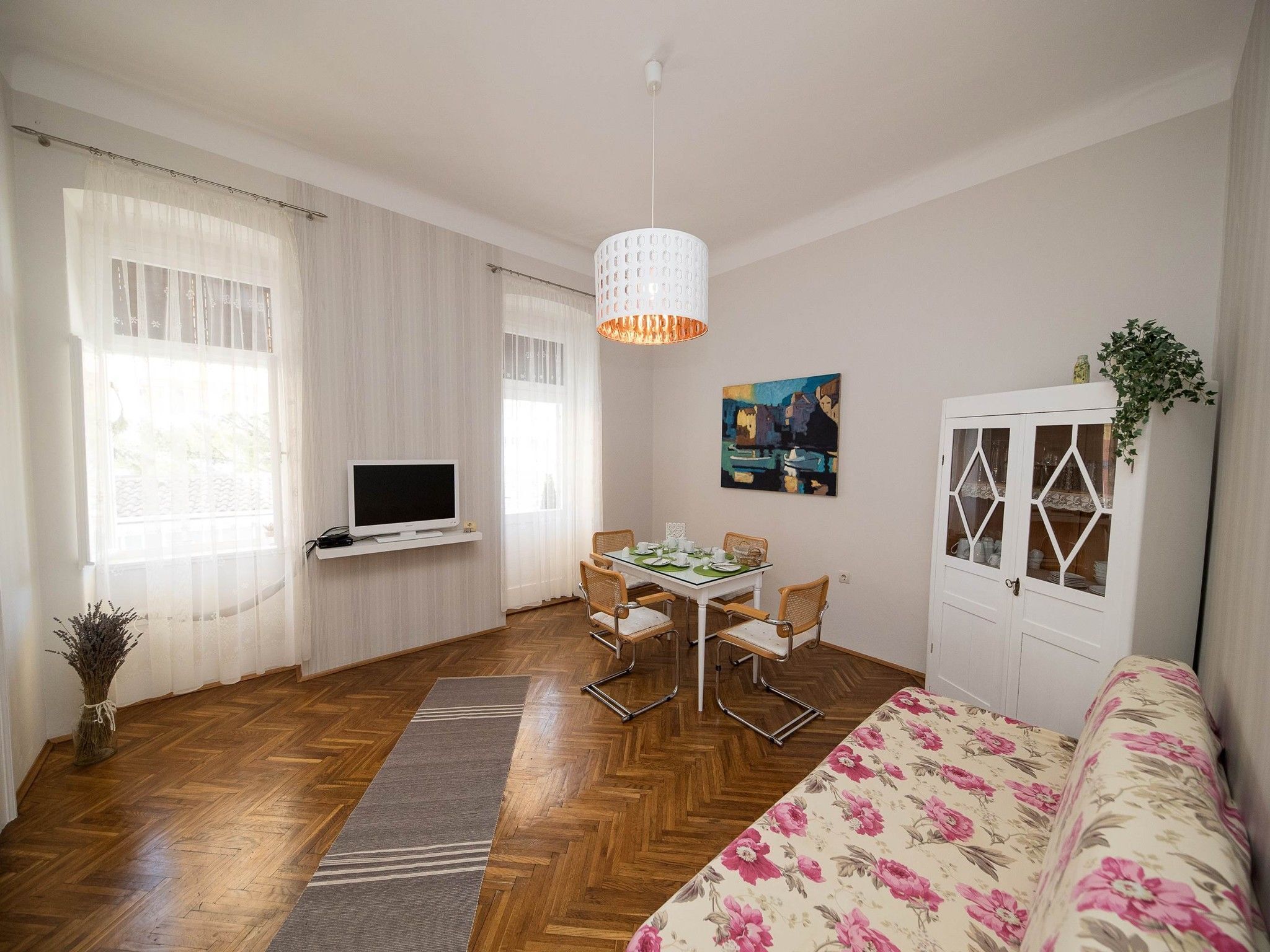 A modern living room with a TV, dining table, chairs, a sofa, and a cabinet.