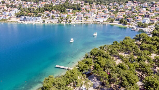 A coastal town with residential buildings, a marina, and clear blue waters. - Apartment Buksa (Trogir)