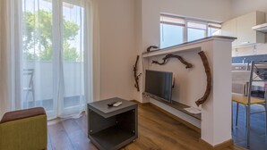 Ein modernes Wohnzimmer mit Flachbildfernseher an der Wand, einer kleinen schwarzen Unterhaltungseinheit und einem Essbereich mit Bar.