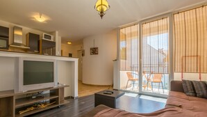 Ein modernes Wohnzimmer mit einer Couch, einem Fernseher und einer Essecke mit Stühlen.
