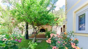 Ein Garten mit einem steinernen Torbogen, einer Holzbank und blühenden Blumen.