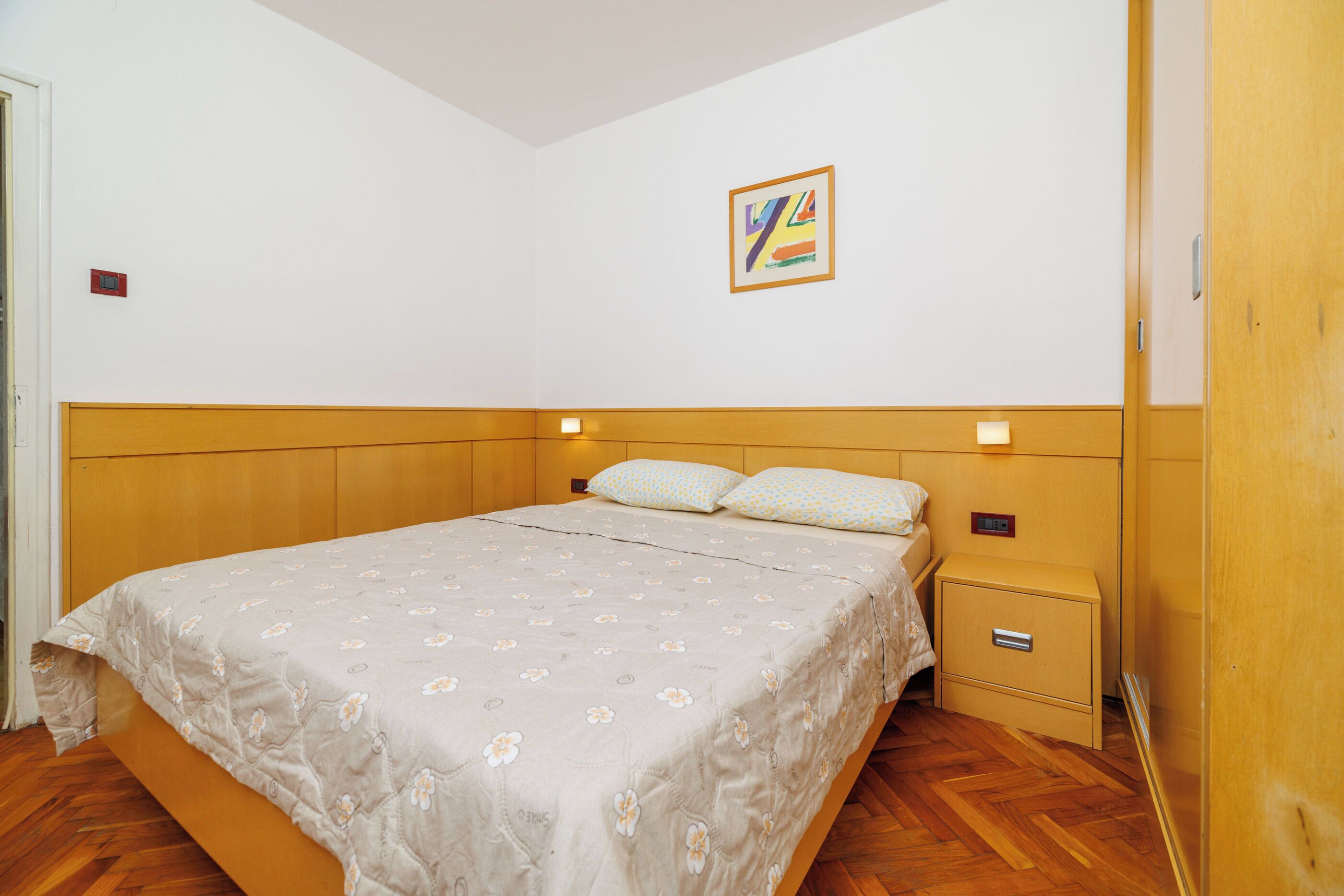 Une chambre à coucher comprenant un lit, une table de chevet et un luminaire fixé au mur.