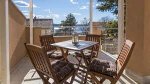 A covered outdoor seating area with a table and chairs, overlooking a scenic view. - Apartment Color Green (Dramalj)