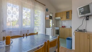 Una cucina compatta con mobili in legno, un forno a microonde, un fornello e una televisione montata a parete.