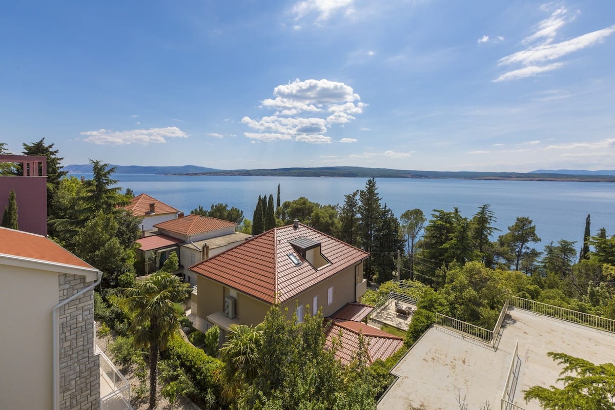 A coastal residential area with houses, a clear sky, and a view of the sea.
