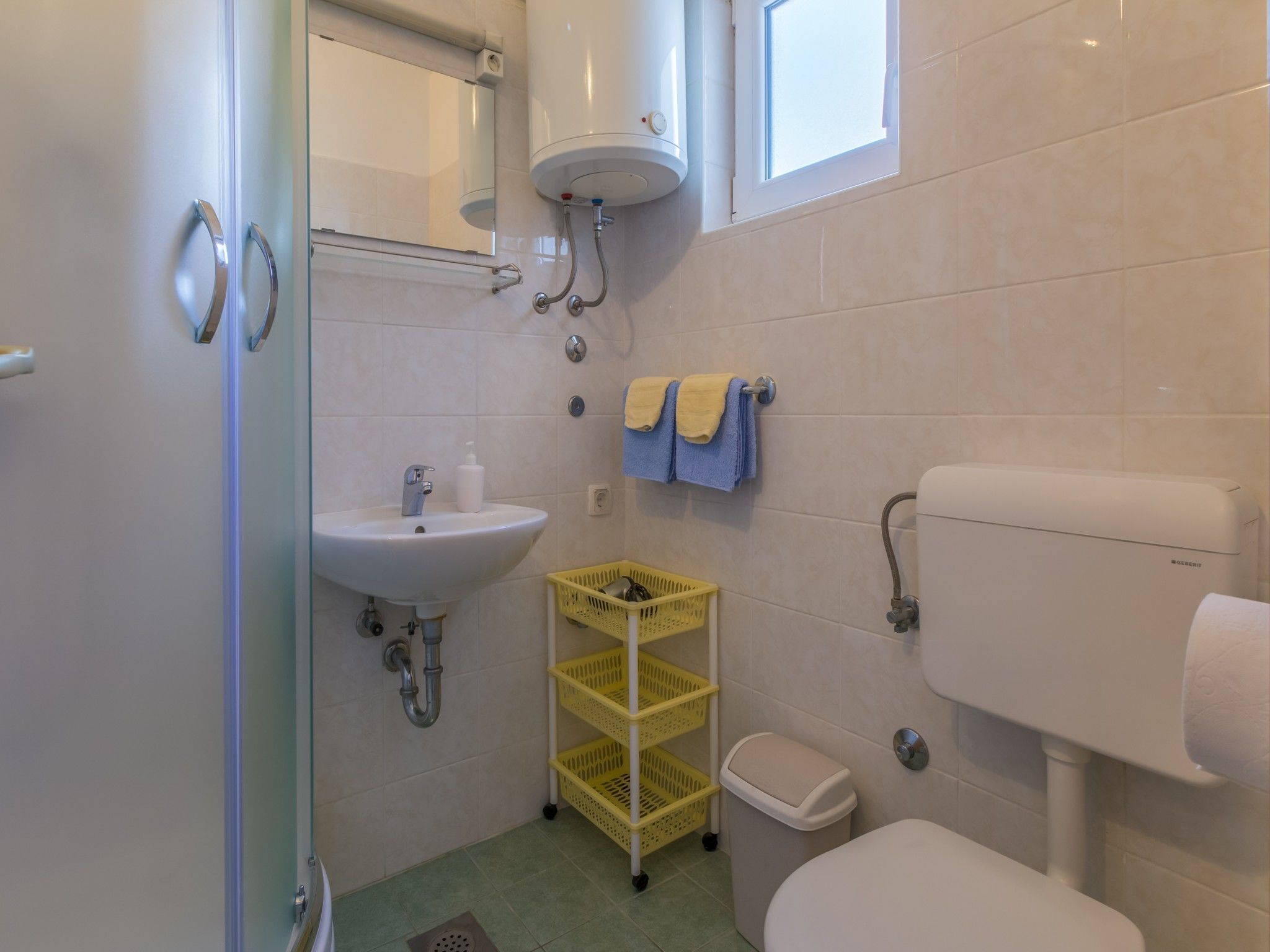 A bathroom with a sink, toilet, and a yellow laundry basket.