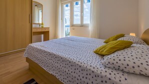 Una camera da letto con un letto, un'armadietto in legno, una finestra con tende e un piccolo tavolo con uno specchio.