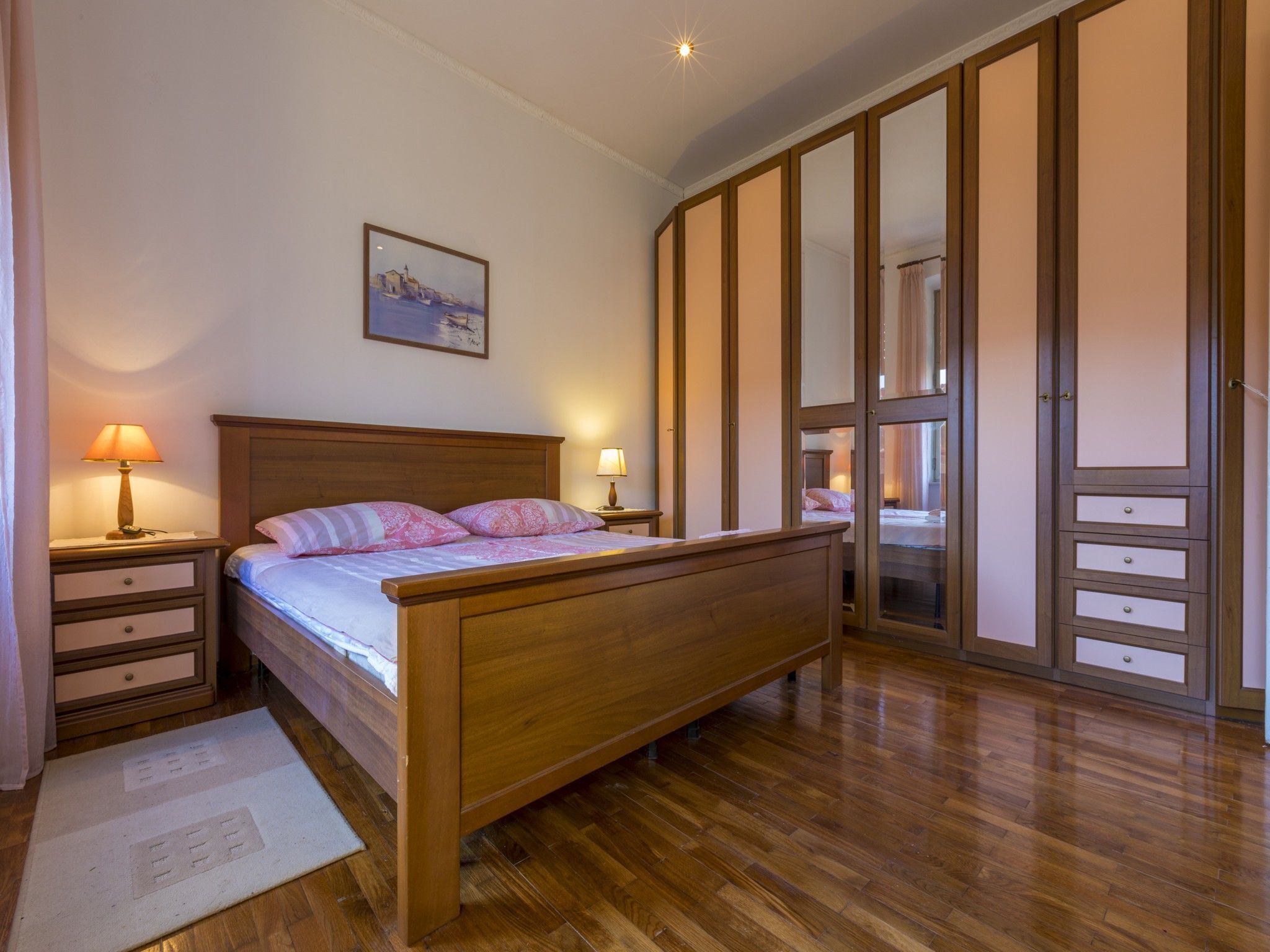 A bedroom with a wooden bed, nightstands, a mirror, and a wardrobe.