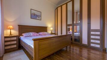 Un dormitorio con cama de madera, mesitas de noche, un espejo y un armario.