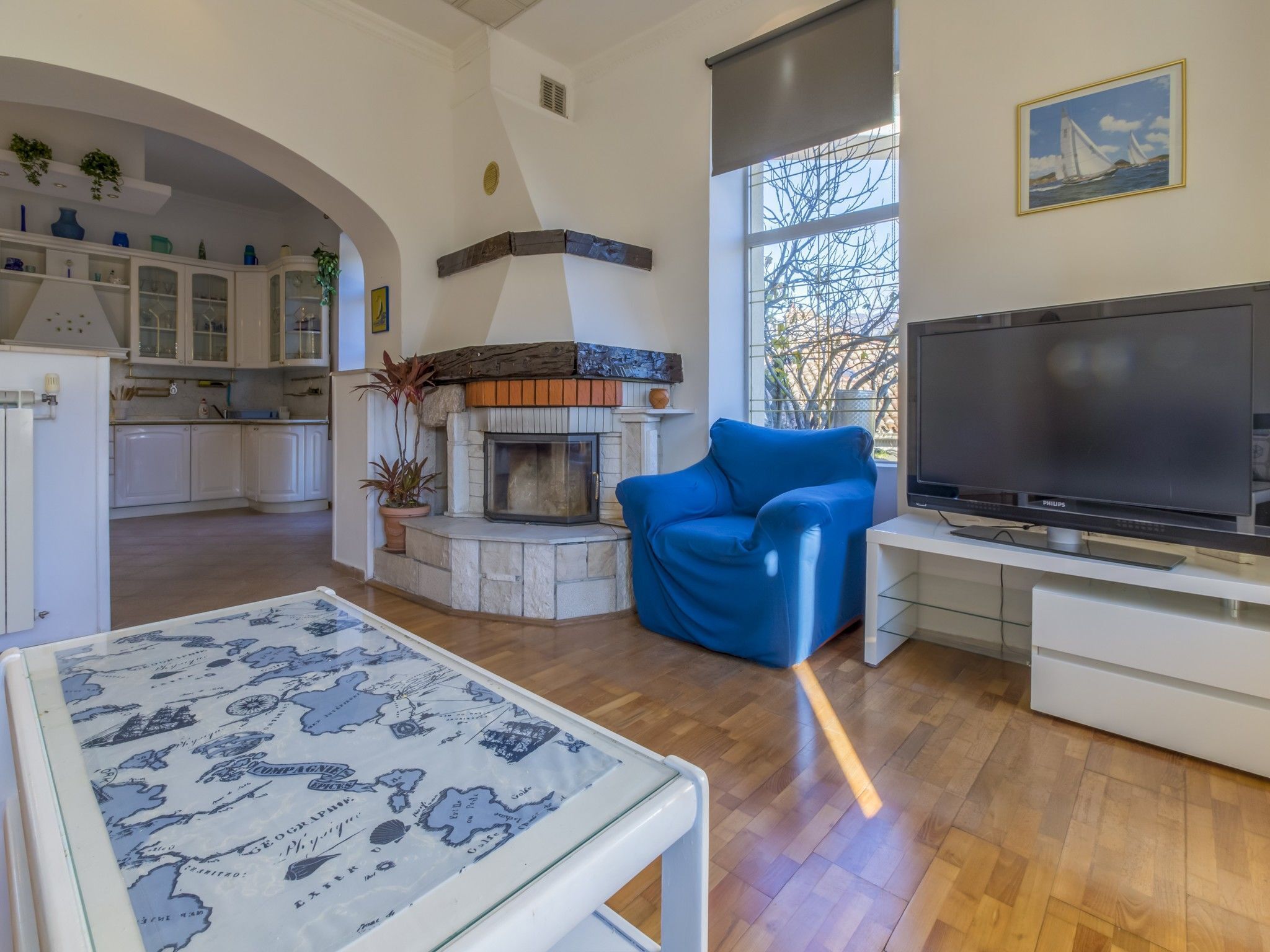 A living room with a fireplace, a television, and a blue armchair.