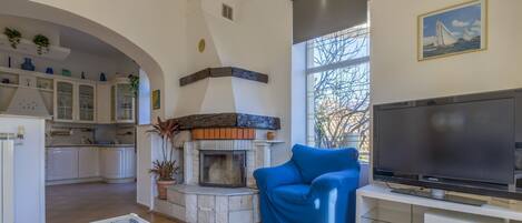 A living room with a fireplace, a television, and a blue armchair.