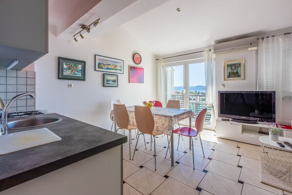 Eine moderne Küche mit Essbereich, einem Fernseher und einem Balkon mit Blick auf die Stadt.