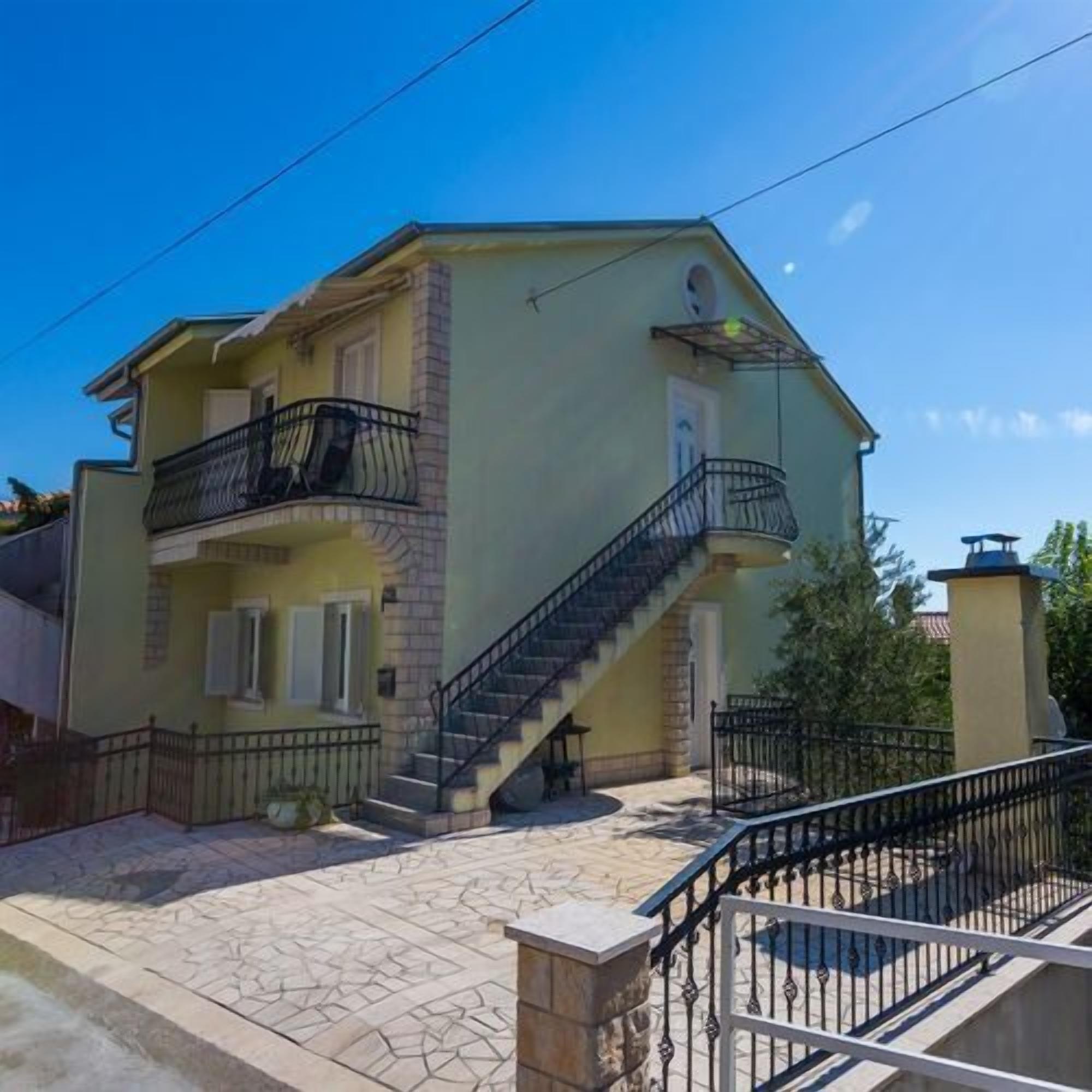 A two-story house with a balcony and a staircase leading to the upper floor.