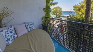 Un balcon avec un lit, une vue sur la mer et un espace de stationnement.