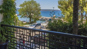 Un balcon donnant sur une marina, avec des bateaux, un ciel dégagé et une végétation luxuriante.