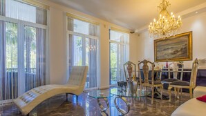 Un salon spacieux avec une table basse en verre, un canapé blanc et un lustre.