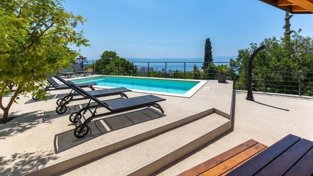 Un espace piscine aménagé sur le toit, avec des chaises longues et une vue sur la mer.