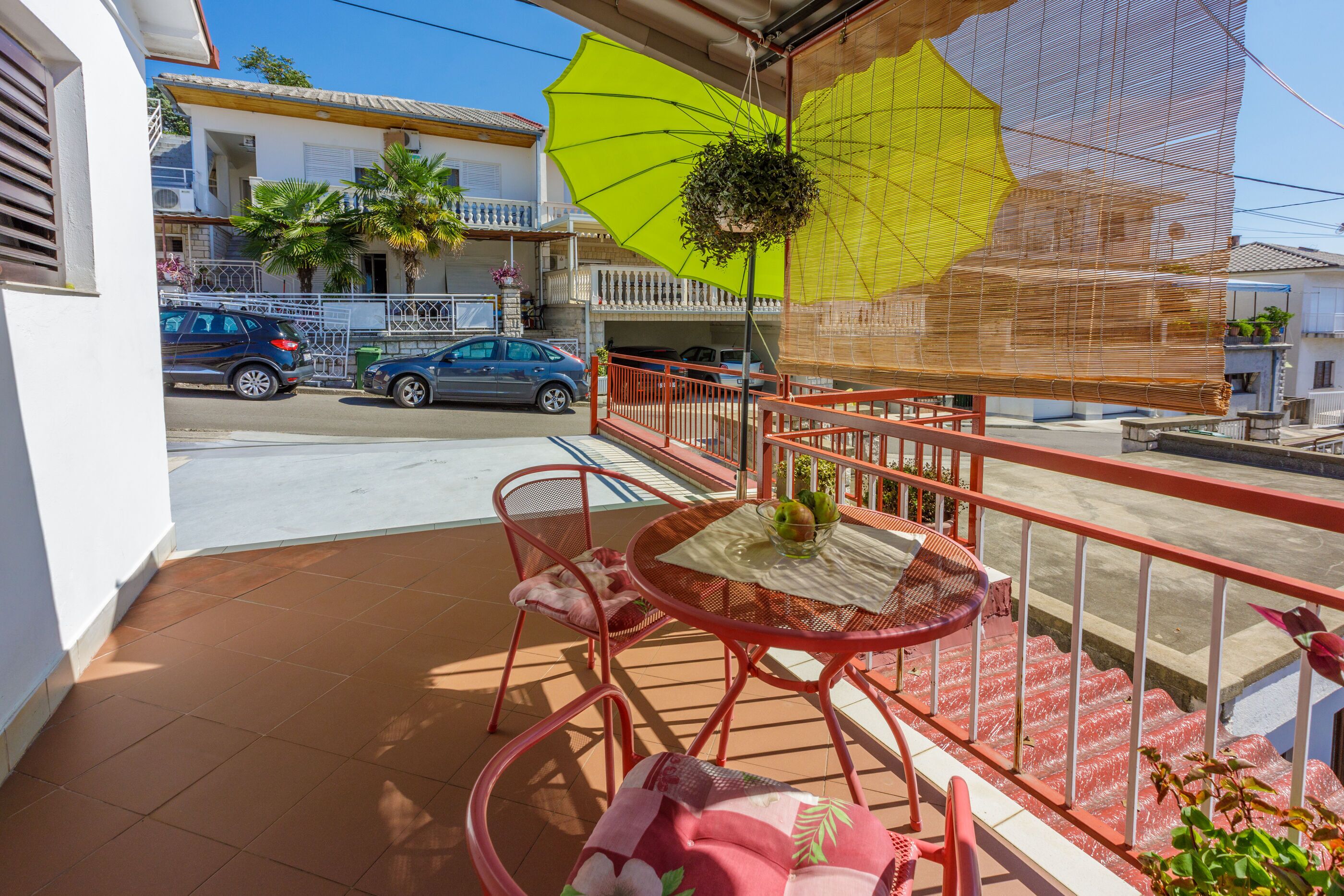 Un balcon avec une table, des chaises et une plante suspendue.