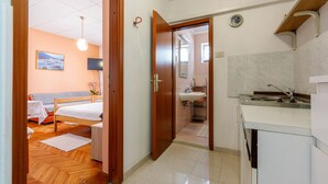 Una camera d'albergo con pavimento in legno, un letto, un comodino, una lampada e un quadro appeso alla parete.