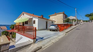 Una strada residenziale con case, un'auto parcheggiata e un cielo azzurro.