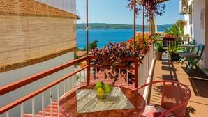 Un balcone con vista sul mare, un tavolo con frutta e piante in vaso.