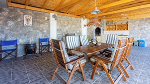 Un comedor rústico con pared de piedra, techo de madera y suelo de baldosas.